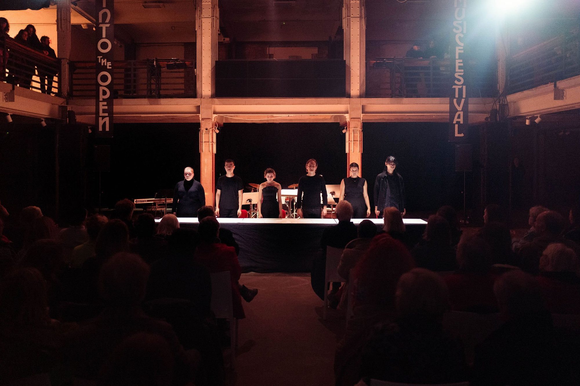 A concert in a wooden festival hall, the ensemble behind a long table