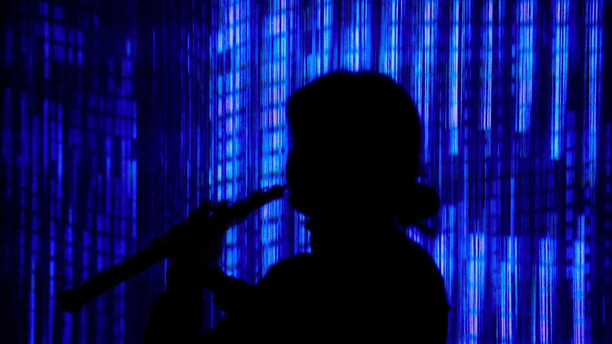 Hands on the oboe in violet light during I would…