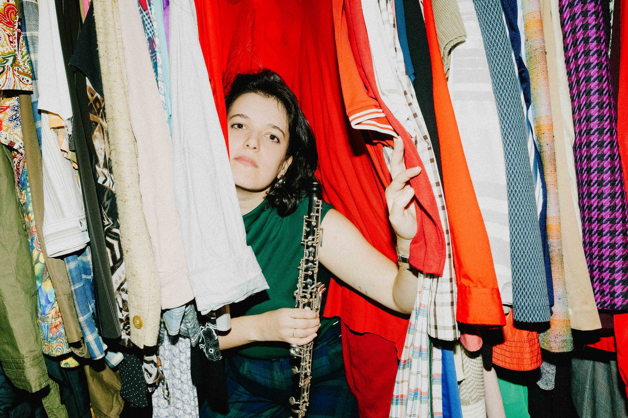 With the oboe between rails of second-hand clothes